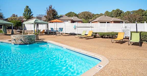 A pool with a stone fountain in the middle of it.