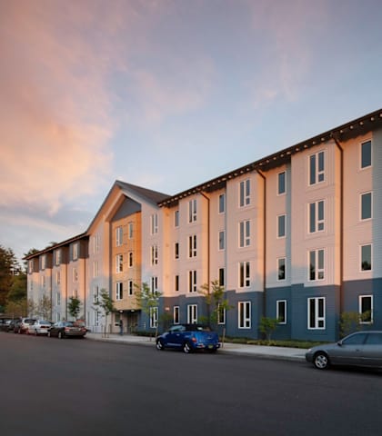 A row of modern apartment buildings with cars parked in front.