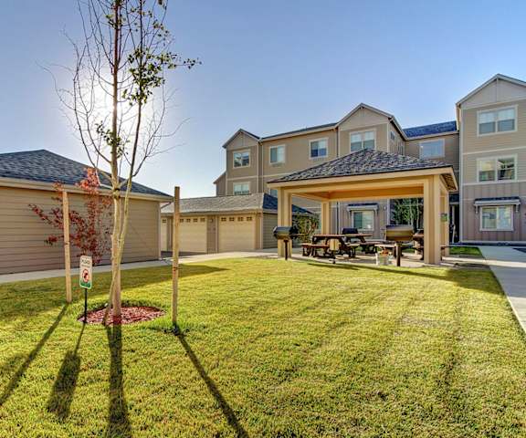 The green space with grass, pathways, the grilling area, and the garages available for rent at Prairie Vista Apartment Homes. 