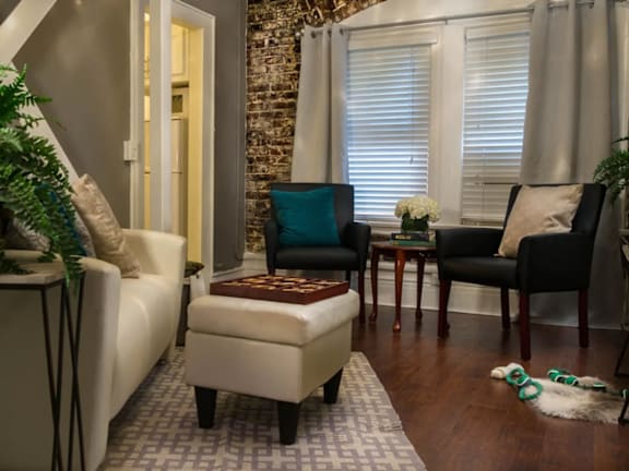 Brookmore living room with a white couch, a black chair, and a potted plant.
