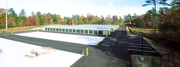 A parking lot with a building in the background and trees in the distance.
