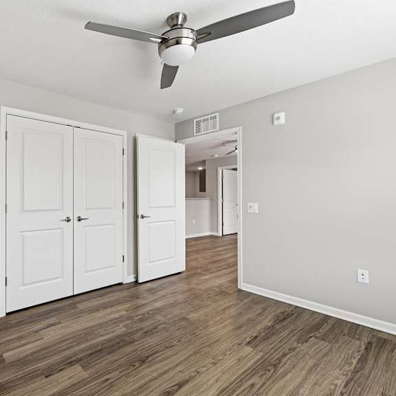 A room with a ceiling fan and four doors.