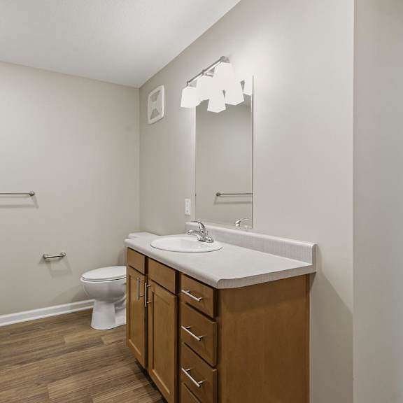 A bathroom with a toilet, sink, and mirror.