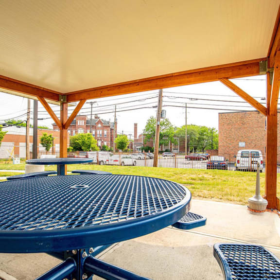 a picnic area with a table and benches and a building in the background