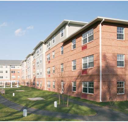a large brick building with green grass and a pathway