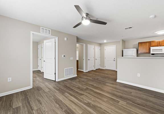 A room with a ceiling fan and wooden flooring.