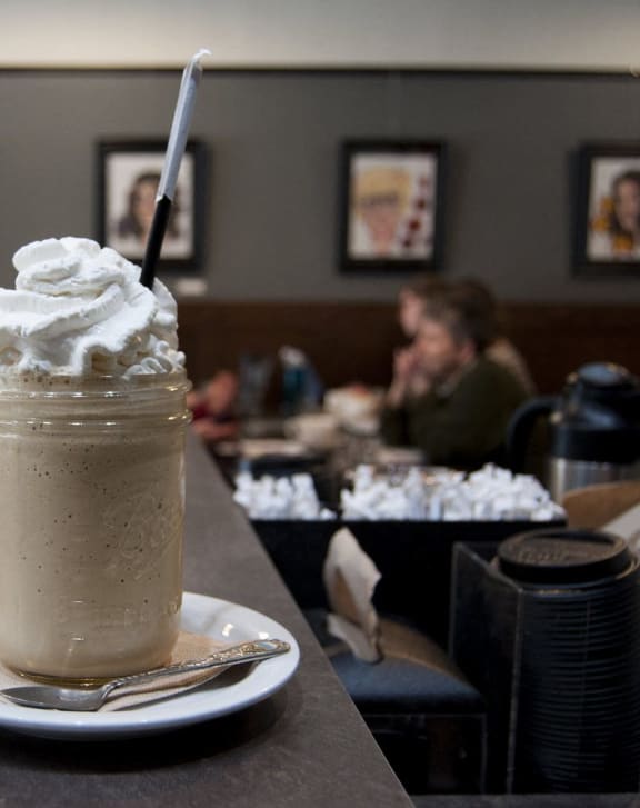 a milkshake sits on a plate at a restaurant