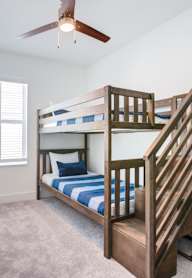 A bedroom with a bunk bed and a ceiling fan.
