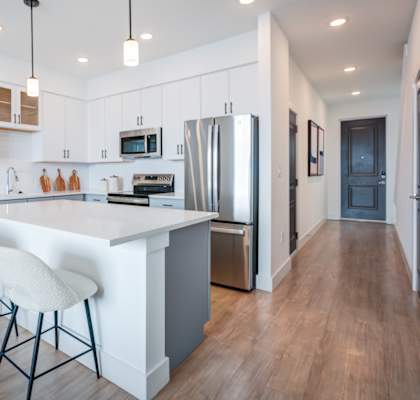 A modern kitchen with white cabinets and a wooden floor.