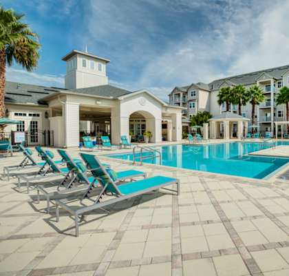 a swimming pool with chaise lounge chairs and a building in the background