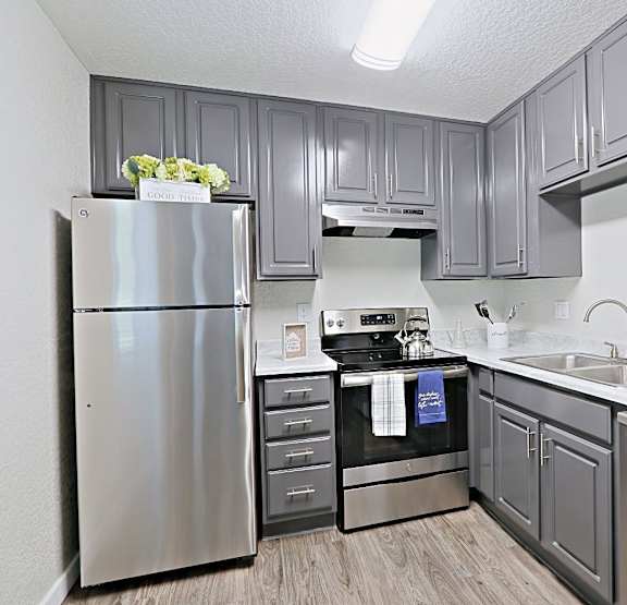 A kitchen with a stainless steel refrigerator, oven, and sink.