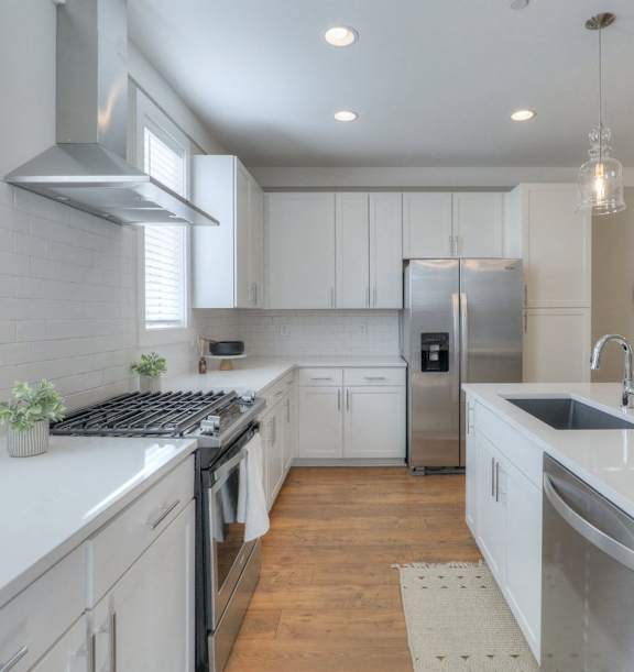 a white kitchen with stainless steel appliances and white counters