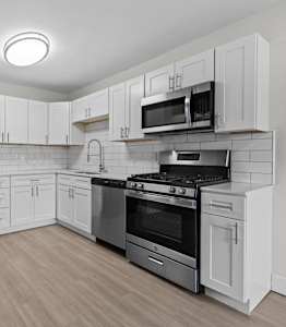 A kitchen with stainless steel appliances and white cabinets.
