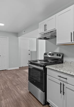 an empty living room with a kitchen and a ceiling fan