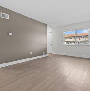 A room with brown walls and wooden flooring with a window.