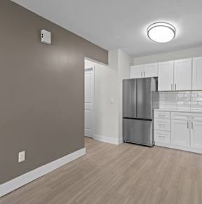 A kitchen with white cabinets and a stainless steel refrigerator.