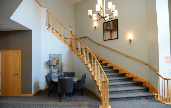 a living room with a staircase and a table and chairs