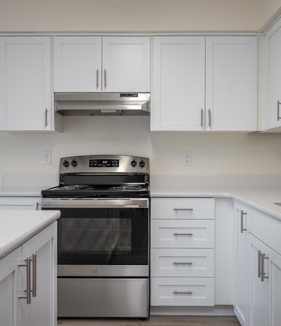 A modern kitchen with white cabinets and stainless steel appliances.