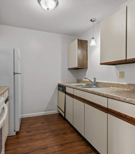 an empty kitchen with white appliances and granite counter tops