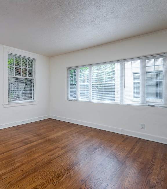 A room with wooden floors and three windows.