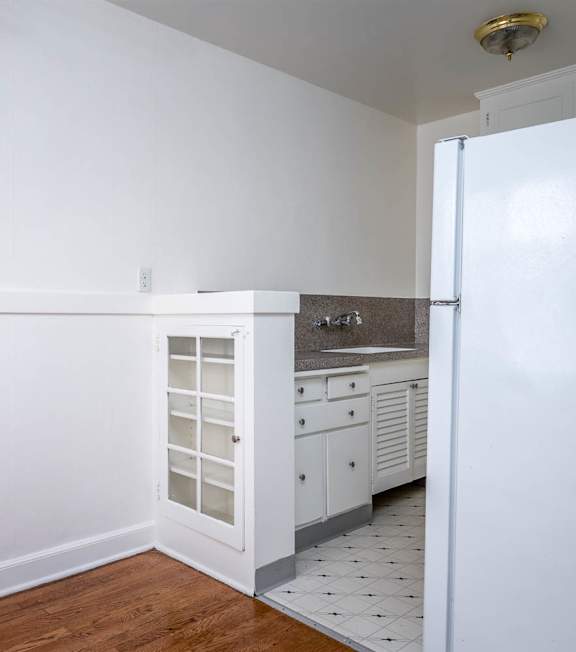A kitchen with white cabinets and a white refrigerator.