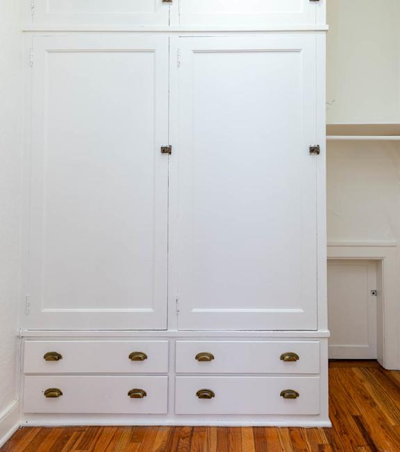 A white wardrobe with four drawers is in a room.