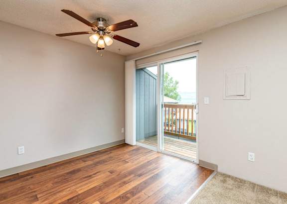A room with a ceiling fan and sliding glass doors leading to a balcony.