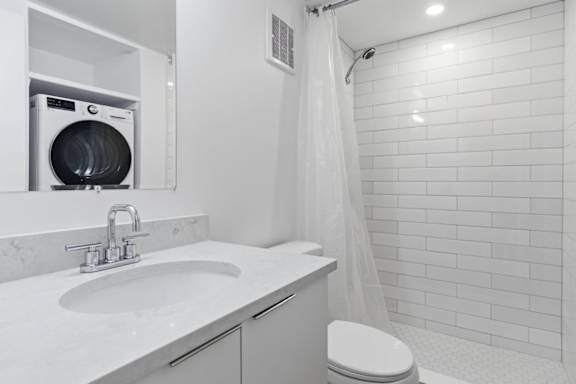 A white bathroom with a toilet, sink, and shower.