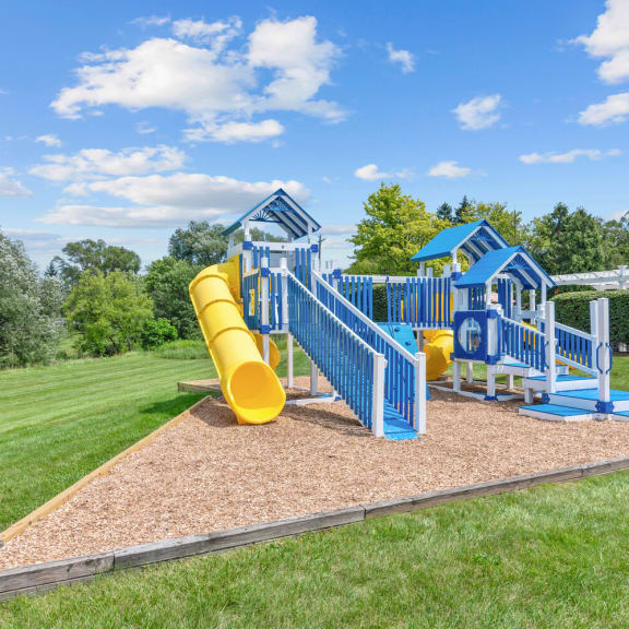 a playground with a yellow slide and blue playset