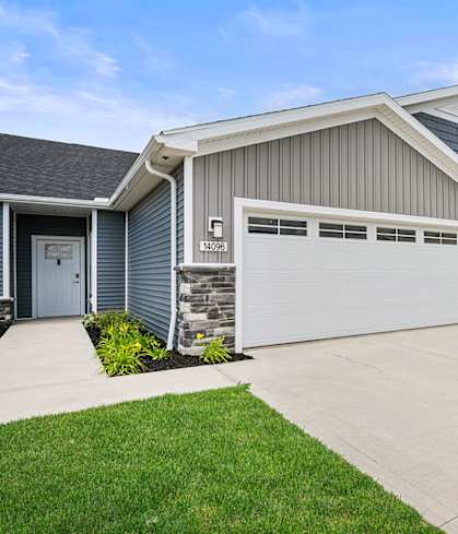 A house with a grey garage door and a stone pillar.
