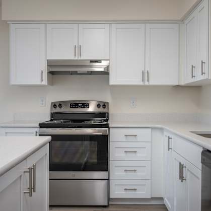 A modern kitchen with white cabinets and stainless steel appliances.