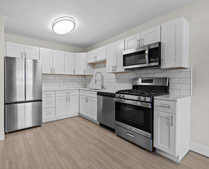 A kitchen with stainless steel appliances and white cabinets.