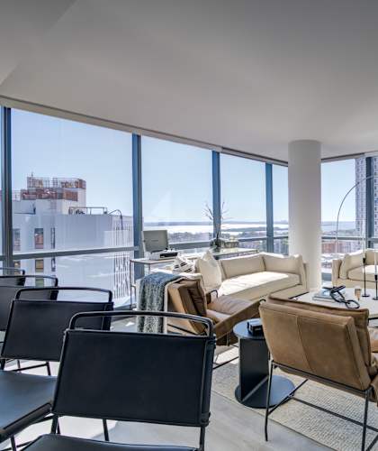 Luxury living room with elegant furniture, a TV, and large windows overlooking the city.