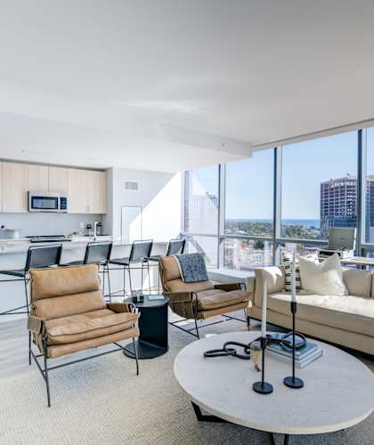 Open-concept living room and kitchen with a large window overlooking the city skyline.