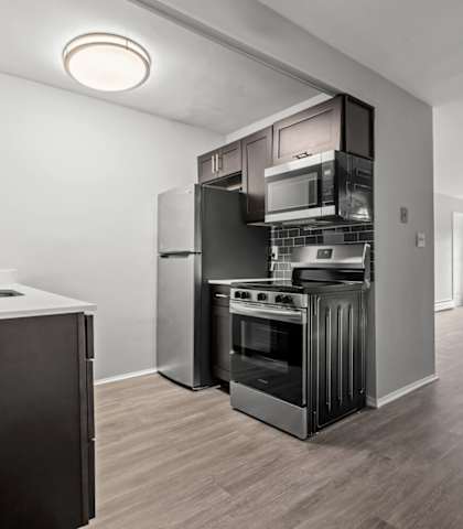 the living room of an apartment with a kitchen and a large window