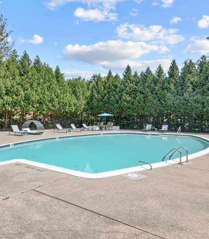 a swimming pool with chaise lounge chairs and trees in the background