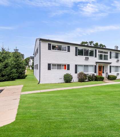 the view of an apartment building with a green lawn