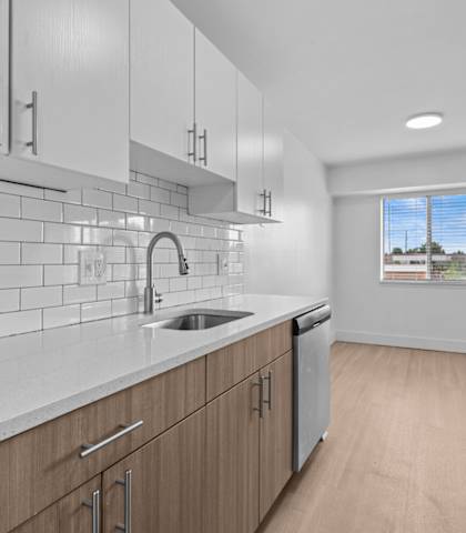 a white kitchen with wooden cabinets and a sink