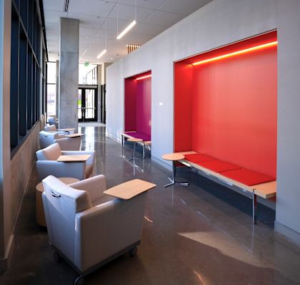 A brightly lit waiting area with a red wall and white furniture.