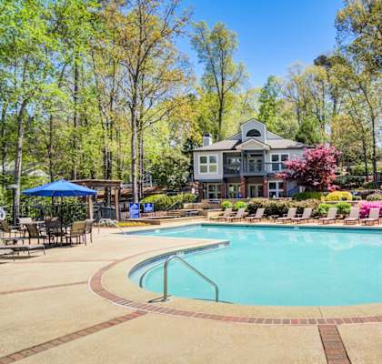 Apartments in Marietta Georgia for Rent – Wood Pointe Apartments - A large swimming pool surrounded by trees and a building in the background.