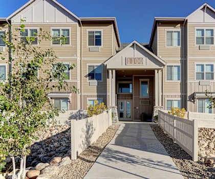 The entrance to the tan buildings at Prairie Vista Apartments, with a walkway surrounded by white picket fences and the building number at the top of the entrance. 