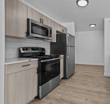 an empty kitchen with stainless steel appliances and wooden cabinets