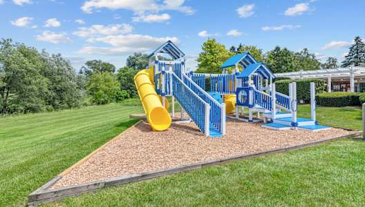 a playground with a yellow slide and blue playset
