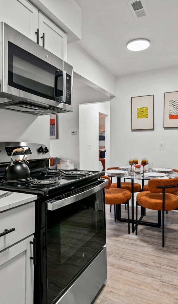 a kitchen with white cabinetry and black appliances  at Park On Canal Apartments, Clinton Twp, MI