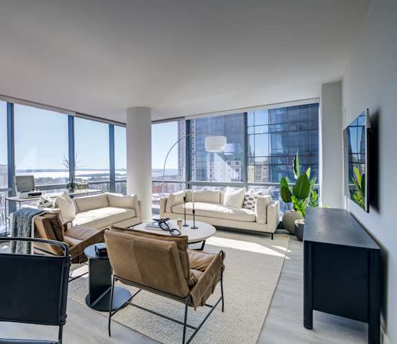 Luxury living room with elegant furniture, a TV, and large windows overlooking the city.