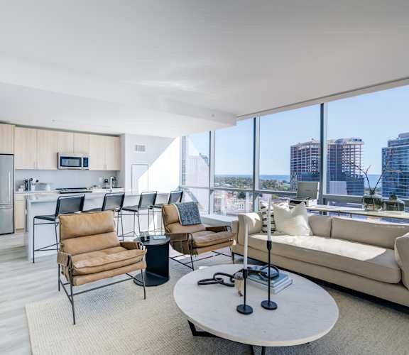 Open-concept living room and kitchen with a large window overlooking the city skyline.
