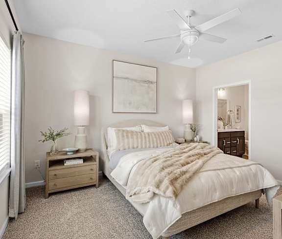 A bedroom with a bed, nightstand, and a ceiling fan.