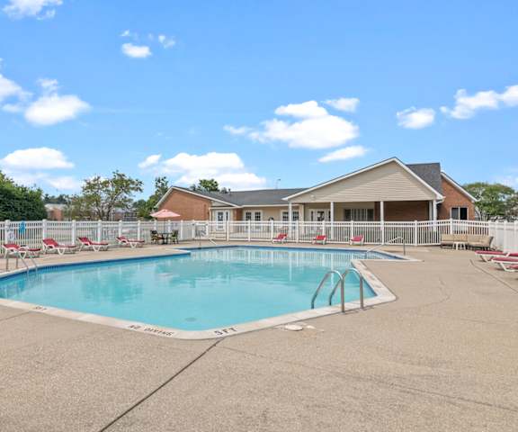 a swimming pool with chaise lounge chairs and a house in the background