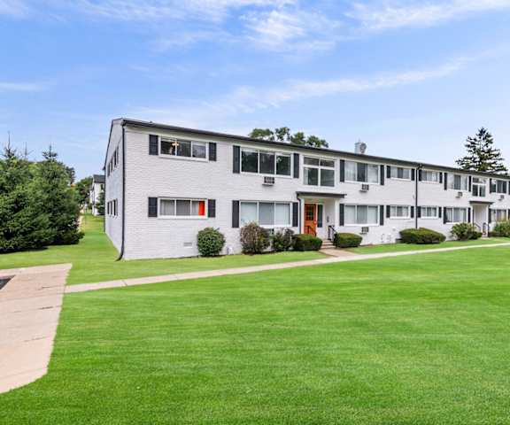 the view of an apartment building with a green lawn