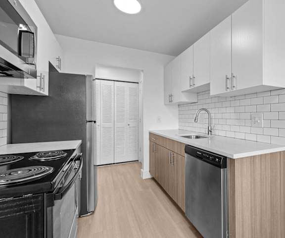 an empty kitchen with stainless steel appliances and wooden cabinets